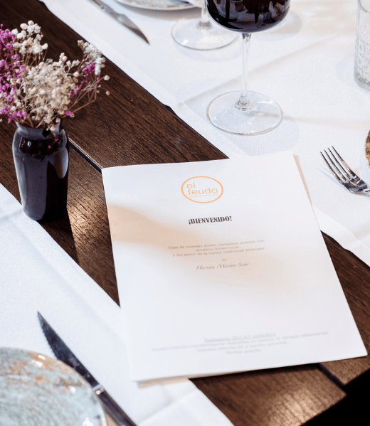 Interior del restaurante El Feudo en Gijón con mesa preparada y carta