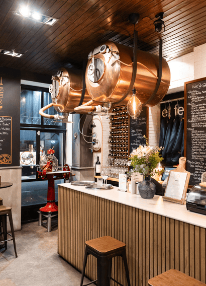 Zona de cocina y vinatería del restaurante El Feudo en Gijón con depósitos de cobre