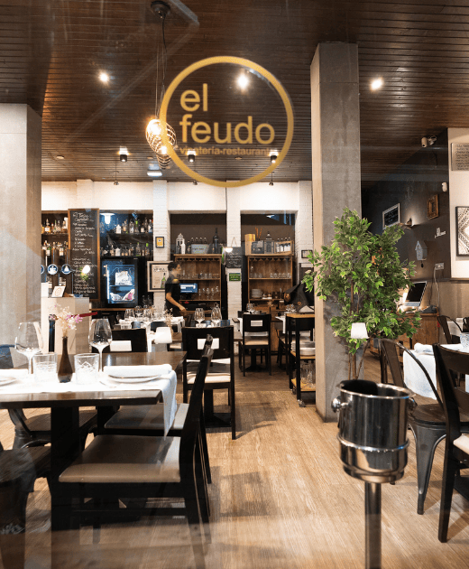 Salón comedor del restaurante El Feudo en Gijón con vinatería y ambiente acogedor